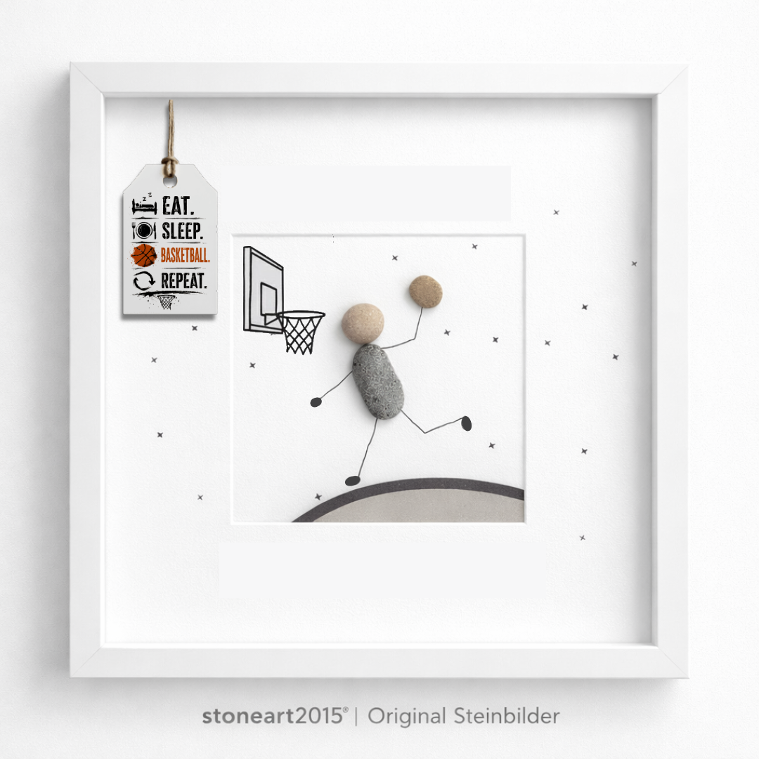 Steinbild mit einem Basketballspieler aus Kieselsteinen beim Korbleger unter einem gezeichneten Basketballkorb, Schriftzug Eat Sleep Basketball Repeat