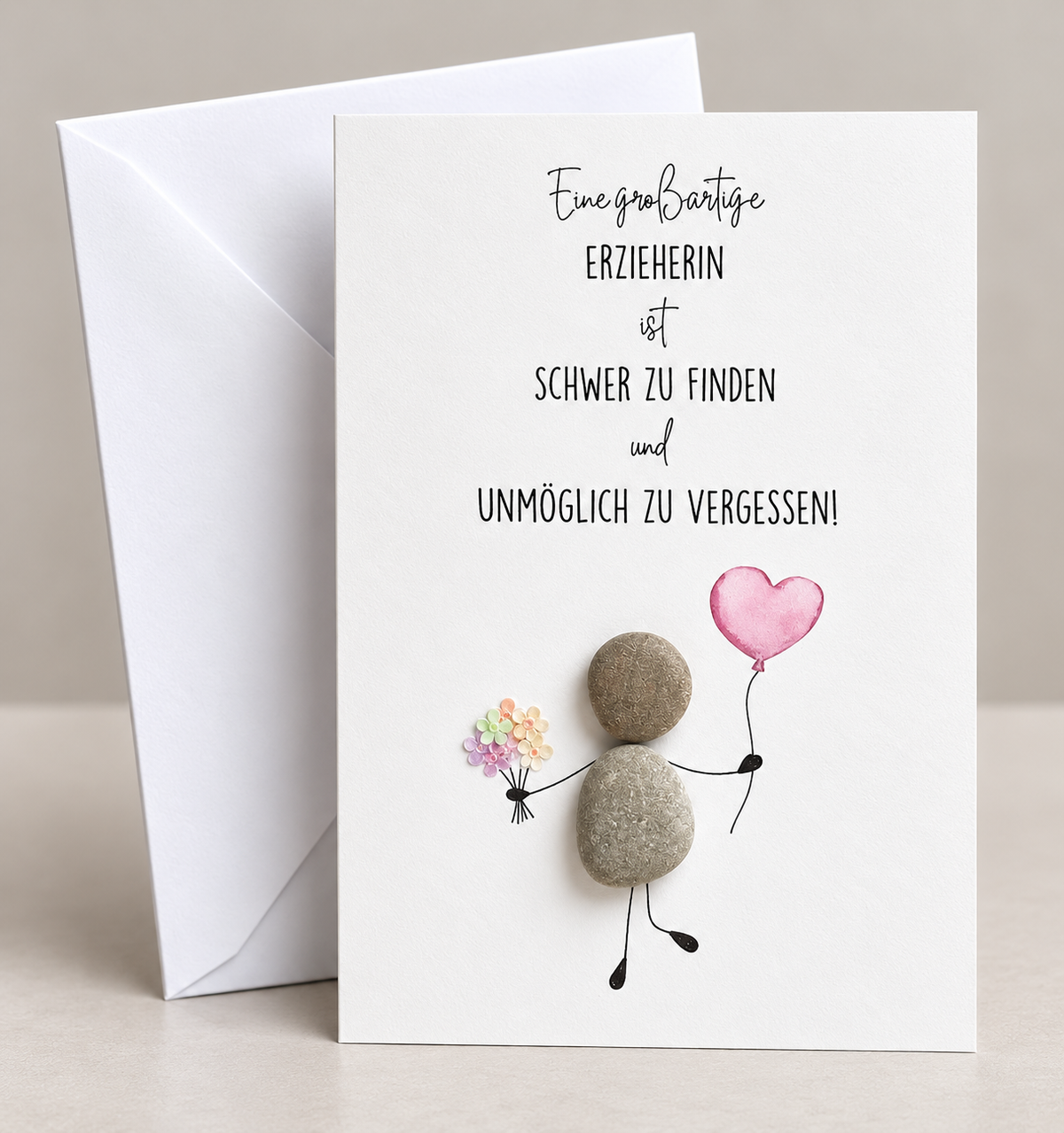 Handgemachte weiße Klappkarte mit Kieselstein-Figur mit Blumenstrauß und rosa Herzballon, Spruch „Eine großartige Erzieherin ist schwer zu finden und unmöglich zu vergessen!“ – Dankeskarte für die Erzieherin, Grußkarte mit Umschlag