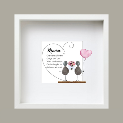 Steinbild mit der Aufschrift „Die wertvollsten Dinge auf der Welt sind selten“ in einem herzförmigen Holzrahmen. Zwei stehende Figuren aus Kieselsteinen mit einem roten Herz dazwischen. Handgefertigte Wanddekoration zum Aufhängen, geeignet als Muttertagsgeschenk.