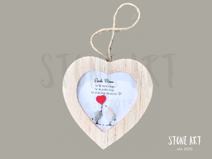 Steinbild mit der Aufschrift „Beste Mama der Welt“ in einem herzförmigen Holzrahmen. Zwei stilisierte Figuren aus Steinen und Holz symbolisieren eine Mutter mit Kind. Wanddeko zum Aufhängen.