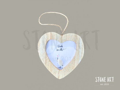 Steinbild mit der Aufschrift „Danke für alles“ in einem herzförmigen Holzrahmen. Zwei aus Steinen gestaltete Figuren stehen nebeneinander, ergänzt durch ein kleines rotes Herz. Handgefertigte Wanddekoration zum Aufhängen.