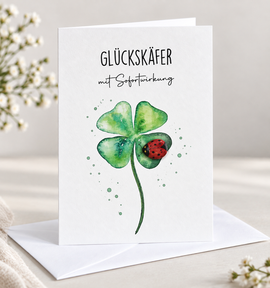 Handgemachte weiße Klappkarte mit Kieselstein, mit Spruch „Glückskäfer mit Sofortwirkung" und Marienkäfer