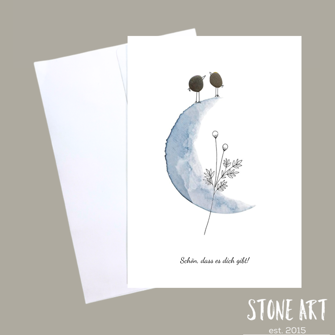 Minimalistische Karte mit zwei aus Kieselsteinen arrangierten Vögelchen und dem Schriftzug ‚Schön, dass es dich gibt‘.