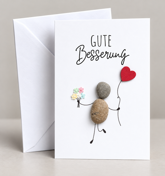 Handgemachte weiße Klappkarte mit Kieselstein, mit Spruch „Gute Besserung" und Mensch mit Herzluftballon