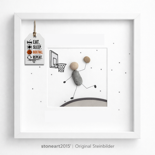 Steinbild mit einem Basketballspieler aus Kieselsteinen beim Korbleger unter einem gezeichneten Basketballkorb, Schriftzug Eat Sleep Basketball Repeat
