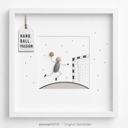 Steinbild mit einem springenden Handballspieler aus Kieselsteinen, der zum Wurf auf ein gezeichnetes Handballtor ansetzt, Schriftzug Hand Ball Passion