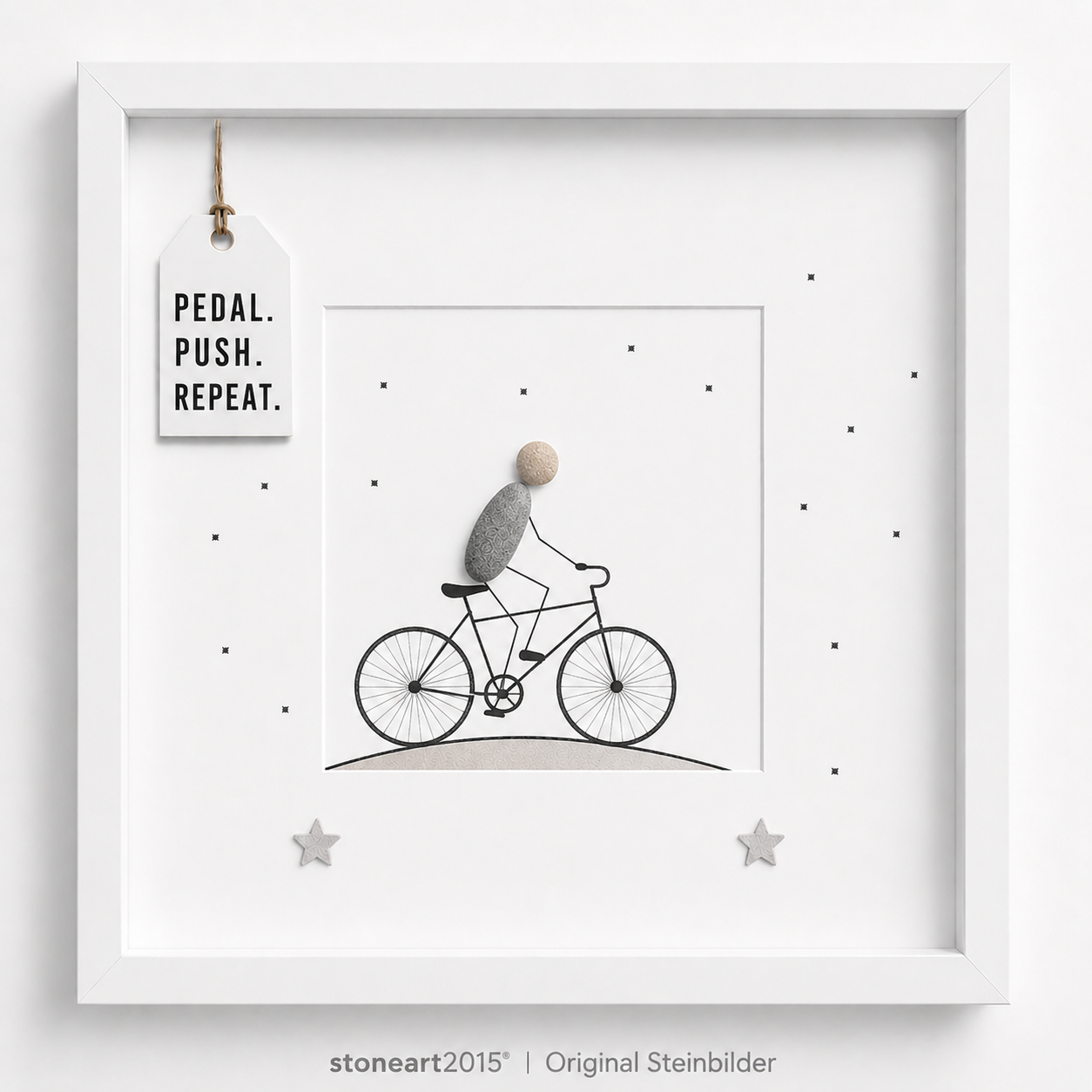 Steinbild mit einem Radfahrer aus Kieselsteinen auf einem gezeichneten Fahrrad, kleine Sterne, Schriftzug Pedal Push Repeat