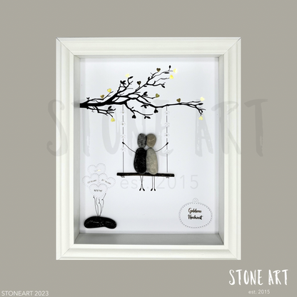 Personalisiertes Steinbild zur Goldenen Hochzeit mit Figurenpaar auf Schaukel unter einem Ast mit goldenen Herzen.