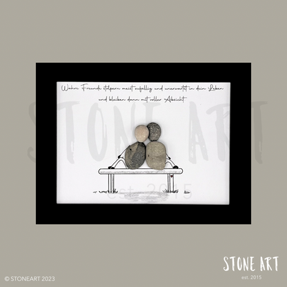 Handgefertigtes Steinbild mit zwei Kieselsteinfiguren auf einer Bank und dem Spruch ‚Wahre Freunde stolpern meist zufällig in dein Leben und bleiben dann für immer‘ – ideales Geschenk für beste Freund:innen.