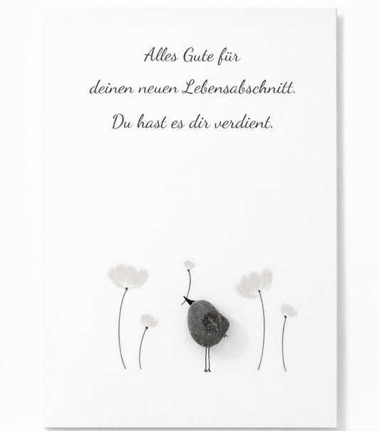 Handgemachte weiße Klappkarte mit Kieselstein-Vogel zwischen zarten Blumen, Spruch „Alles Gute für deinen neuen Lebensabschnitt. Du hast es dir verdient.“ – Karte zum Ruhestand und Neuanfang, Grußkarte