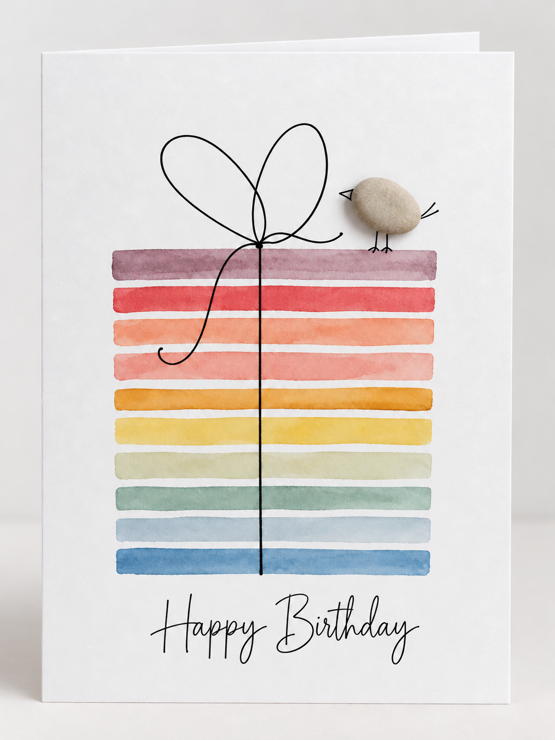 Handgemachte weiße Klappkarte mit Kieselstein-Vogel auf einem bunten Aquarell-Geschenk mit Schleife, Schriftzug „Happy Birthday“ – Geburtstagskarte, Grußkarte mit Umschlag