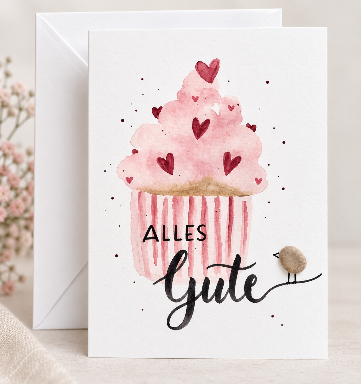 Handgemachte weiße Klappkarte mit Kieselstein-Vogel und Cupcake mit Herzen, Spruch „Alles Gute“ – Geburtstagskarte und Glückwunschkarte, Grußkarte mit Umschlag