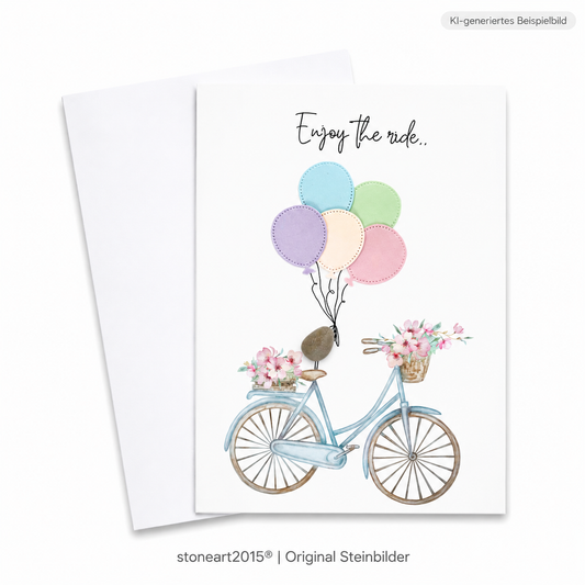 Handgemachte weiße Klappkarte mit Kieselstein-Figur, Fahrrad mit Blumenkörben und bunten Luftballons, Schriftzug „Enjoy the ride“ – Karte für ein Geldgeschenk zum Fahrrad, Grußkarte mit Umschlag